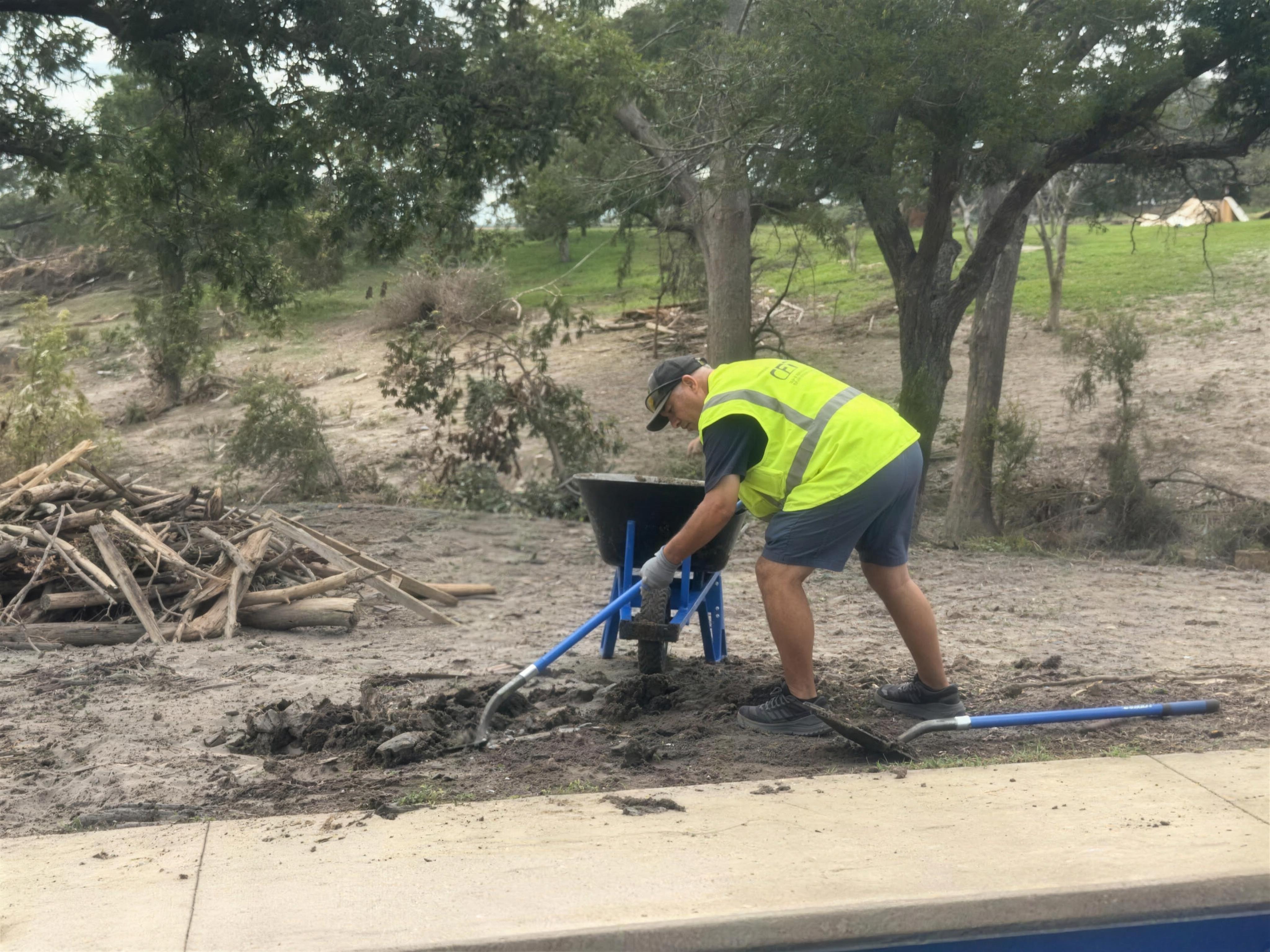 Volunteer raking flood mud from a property in the Texas Hill Country