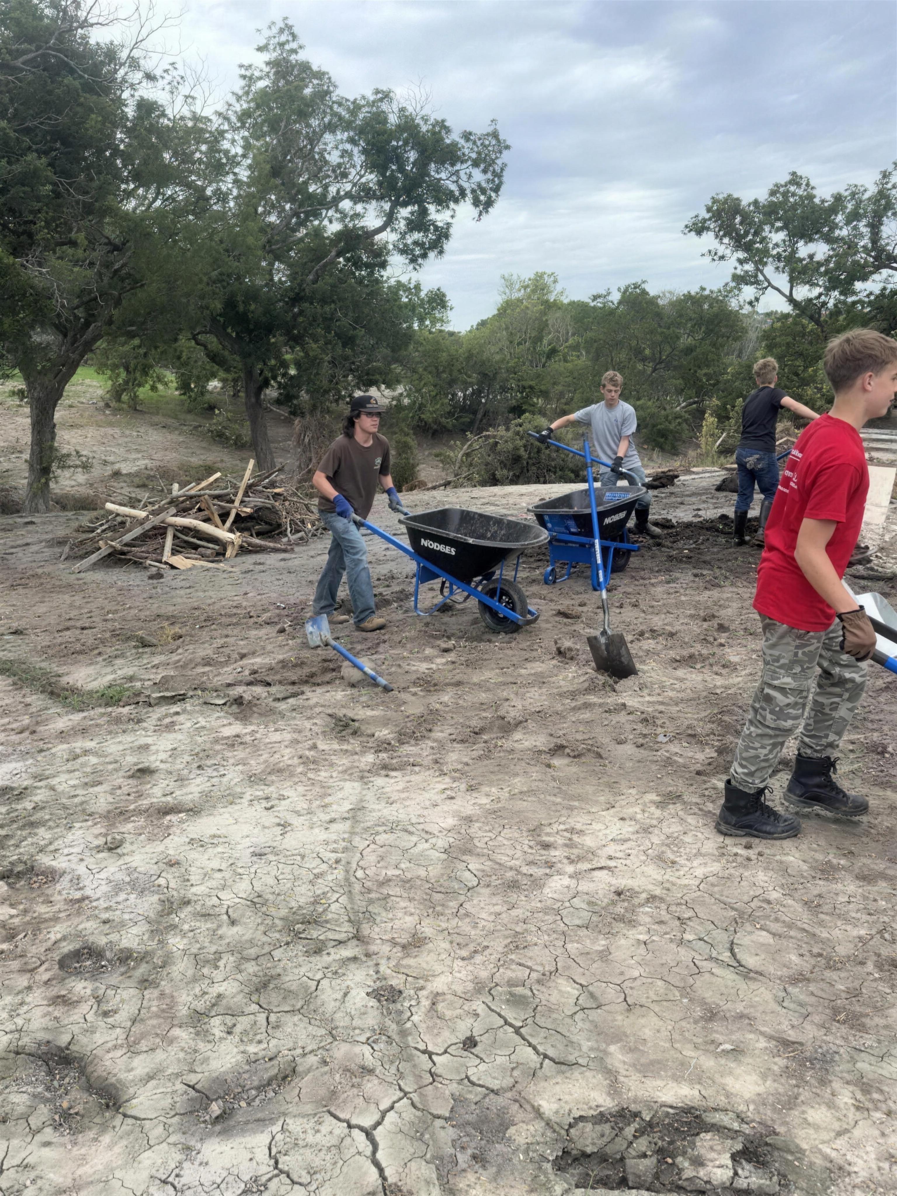 Volunteers shoveling flood mud from a yard in the Texas Hill Country