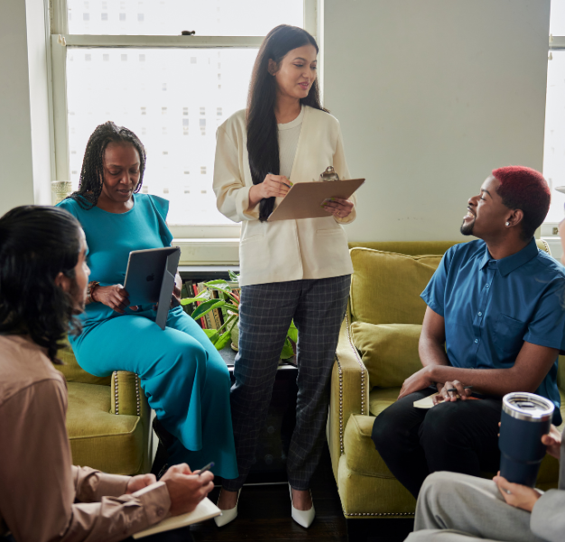 A leader standing up surrounded by her team.