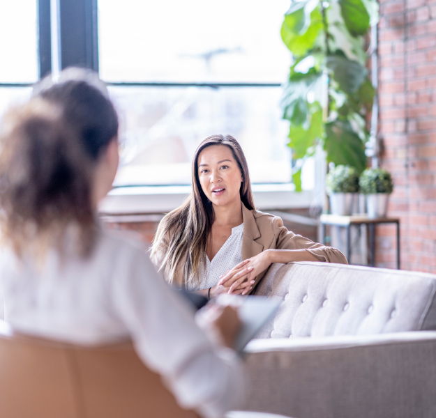 Two women sitting across from one another talking.