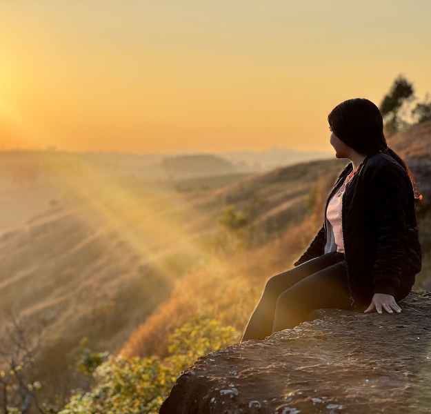 Person sitting on a mountain top looking out