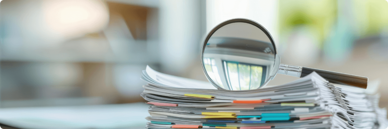 Une loupe posée sur une pile de documents, représentant le contrôle accru de la formation professionnelle.