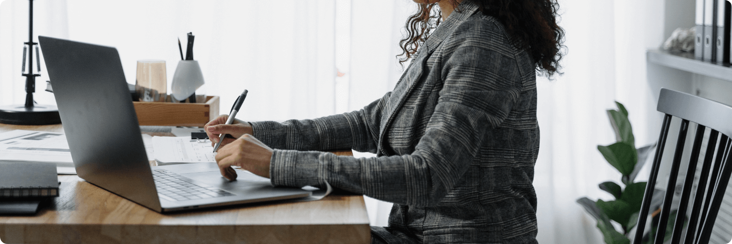 Photo d'une personne assise à un ordinateur effectuant les tâches quotidiennes administratives d’un OF avec un logiciel de gestion.