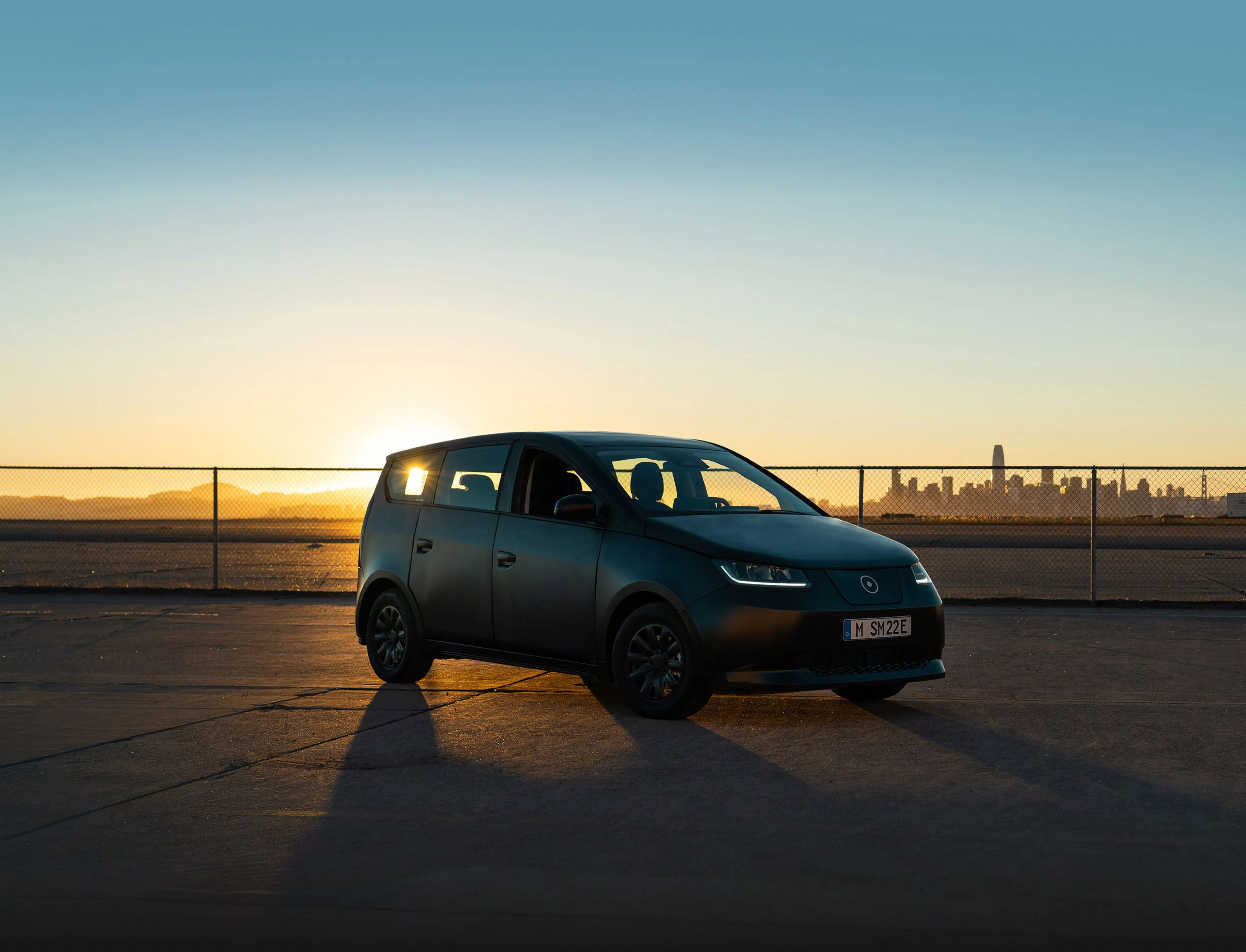 a car parked on a road in front of a sunset