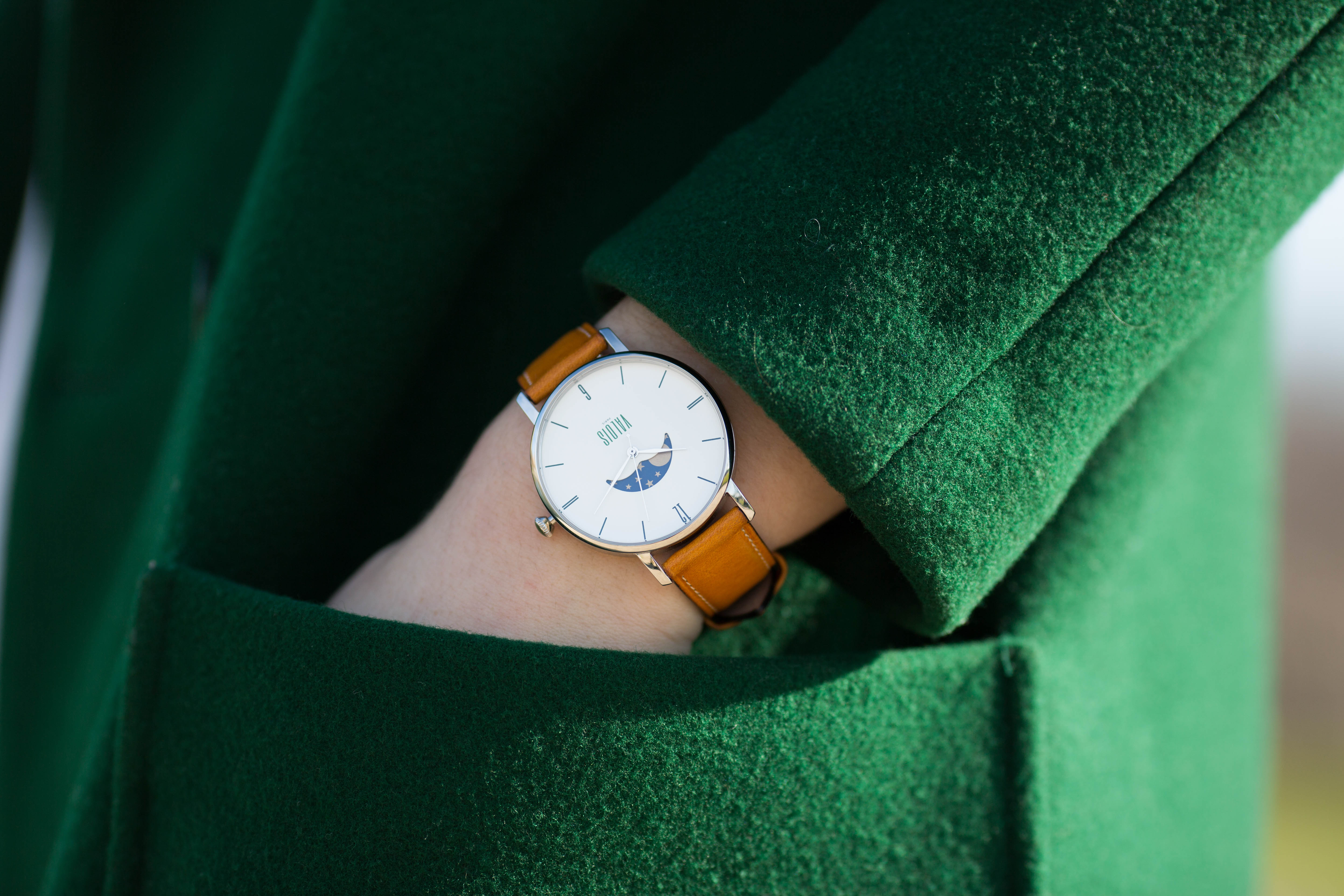 Montre valois bracelet en cuir gold portée par une femme au manteau vert