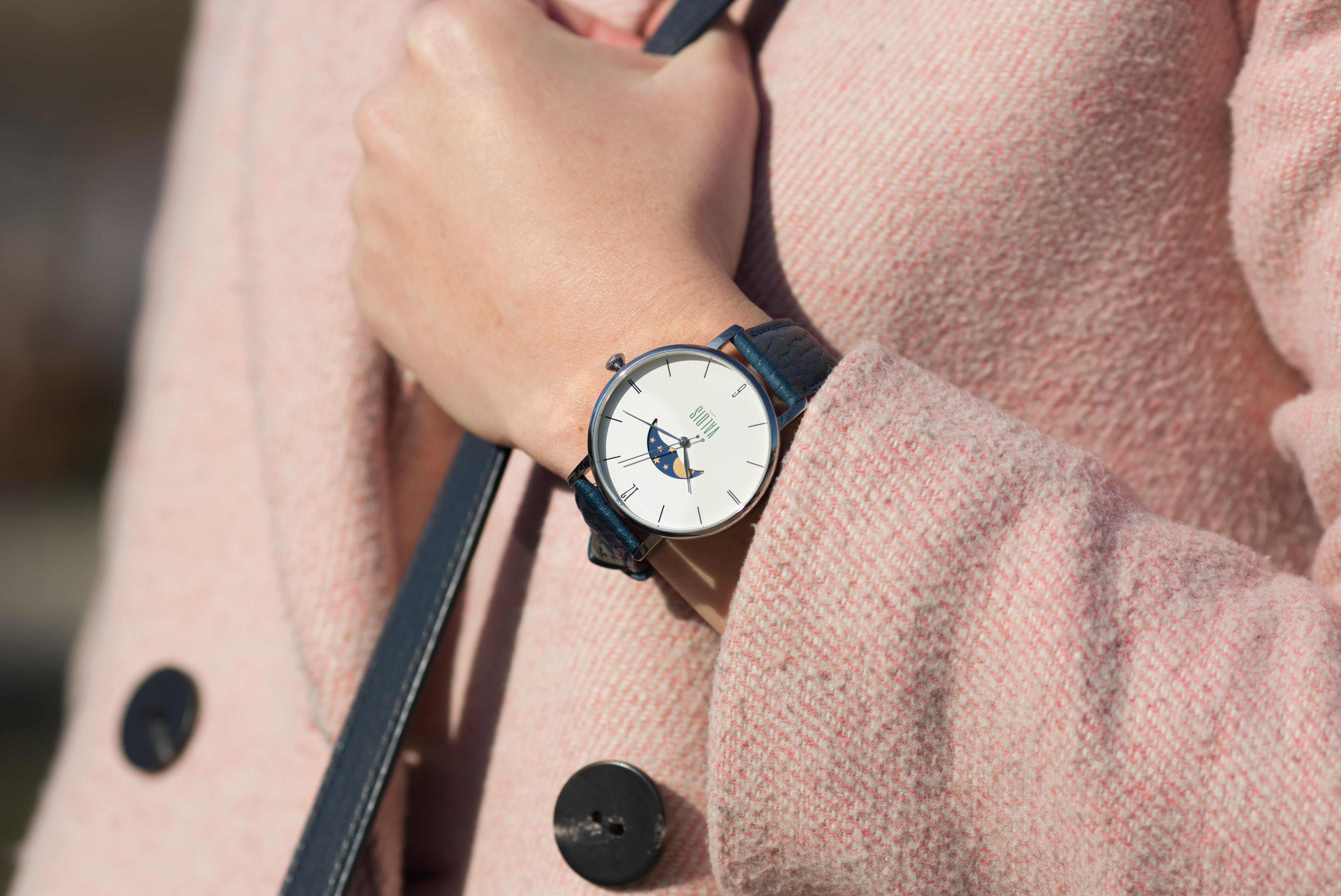 Montre Valois bracelet en cuir bleu portée par une femme au manteau rose