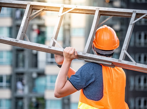 Construction Worker Carries Step Ladder
