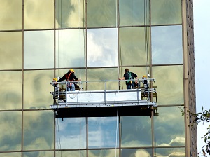 Two workers on a suspended scaffold on a building.