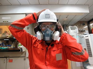 Worker wearing a respirator, safety glasses, ear muffs and a hard hat.