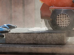 A masonry saw cutting concrete pavers using the wet method.