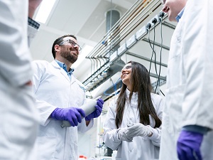 Laboratory workers in lab coats talking to each other and smiling.