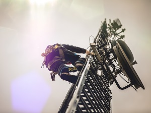 Worker wearing fall protection climbing up a tower.