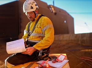 A construction worker on site filling out a job hazard analysis form.