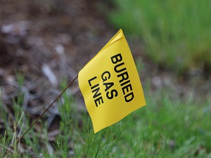 A small yellow utility flag in the grass that says "Buried Gas Line."