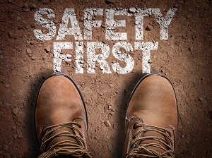 Work boots shown on a dirt floor with the words "Safety First".