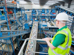 Supervisor wearing a hard hat and safety vest is overseeing the recycling plant with several conveyor systems.