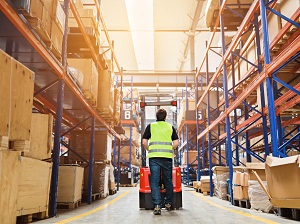 Warehouse worker pushing a pallet jack.