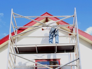 Worker on a scaffold making roof repairs.