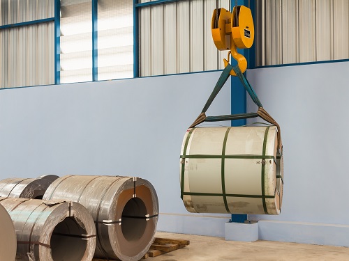 An overhead crane lifting a heavy role of material.