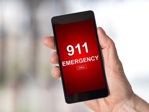 Hand holding a phone that says 911 Emergency on a red screen.