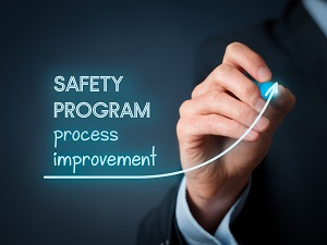 A man drawing an arrow pointing up with words that say Safety Program Process Improvement.