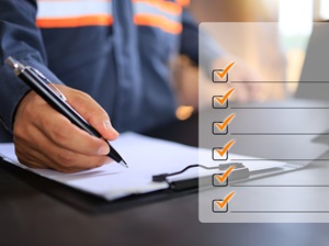 A person in safety gear writing on a clipboard, with a semi-transparent checklist overlay.