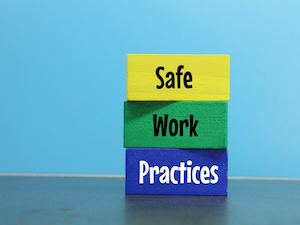 Three colorful wooden blocks stacked on top of each other with the words “Safe,” “Work,” and “Practices” against a blue background.