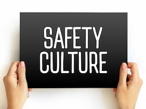 Hands holding a black sign with bold white text reading “Safety Culture” against a white background.
