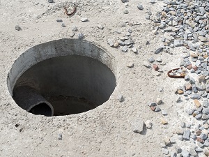 View of a hole cut into concrete, you can see the pipes inside.