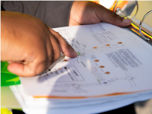 Close-up of a person’s hand pointing to a printed site map with traffic flow diagrams, used as part of an internal traffic control plan.