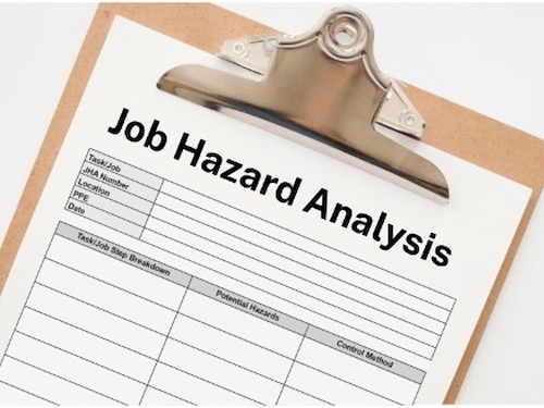 Clipboard with a printed Job Hazard Analysis form showing columns for job steps, potential hazards, and control methods.