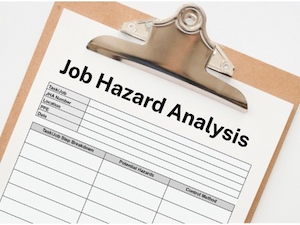 Clipboard with a printed Job Hazard Analysis form showing columns for job steps, potential hazards, and control methods.