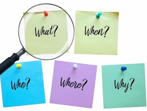 Colorful sticky notes pinned on a board with words “What?,” “When?,” “Who?,” “Where?,” and “Why?” under a magnifying glass.