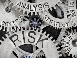 Close-up of metal gears with engraved words including “Risk,” “Analysis,” “Control,” and “Strategy,” symbolizing hazard management.