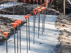 Rebar with protective caps sticking out of hard concrete.