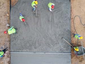 Overhead view of several workers spreading out wet concrete.