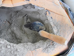 A bag of dry cement with a small shovel in it.