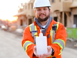 Construction Worker Holding Hand Soap in Front of Construction Site