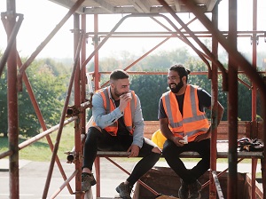 Two Construction Workers Sitting on Scaffolding Eating Lunch, Taking a Break