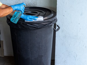 Gloved Hands Disinfecting the Lid of a Trash Can