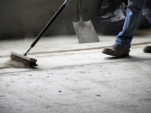 Worker sweeping up a dirty floor.