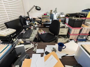 A very messy desk with a lot of papers piled up everywhere.