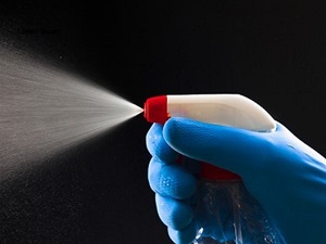 A person wearing a rubber glove spraying a cleaning chemical.