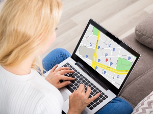 A person on a laptop looking at a map at home before they drive to a destination.