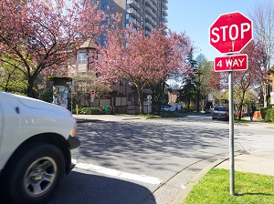 A car carefully stopped behind a stop sign in a suburban intersection.