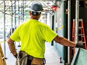 Construction worker at a construction site with a step ladder in the background on the job site.