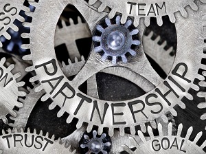 A graphic of several gears that represent working together with words like team, partnership, trust, and goal.