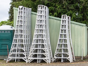 Several tripod orchard ladders folded up and ready to use.