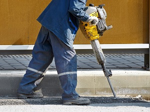 Worker using a jackhammer on a construction site.