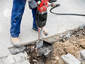 Worker using a jackhammer on a construction site.